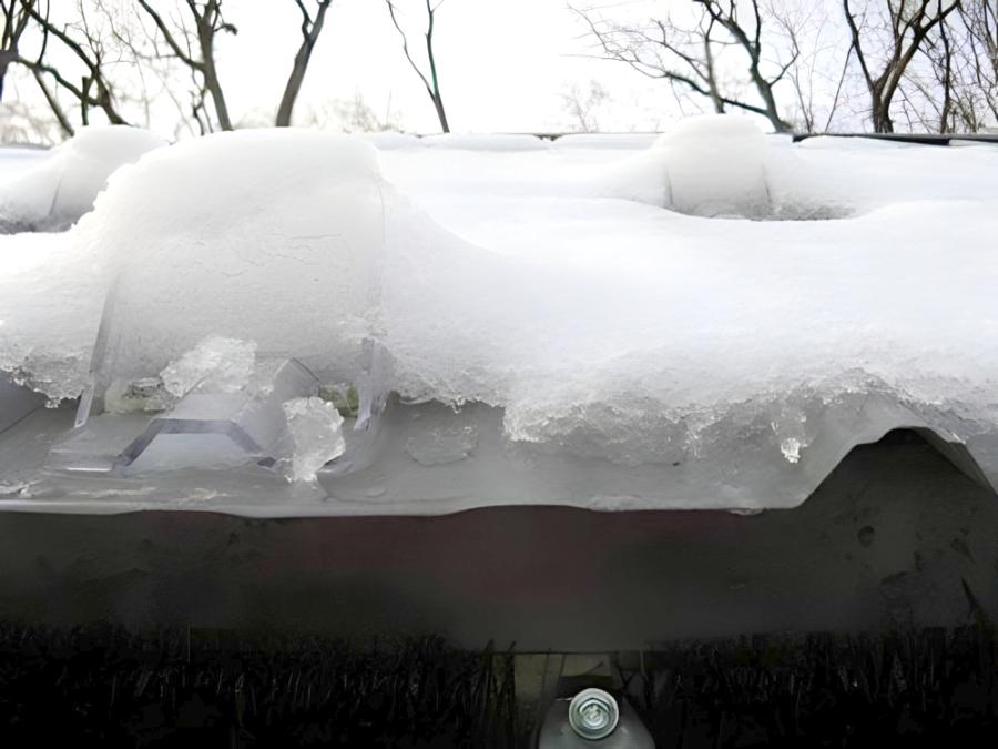 Closeup of multiple Icejax I snow guards mounted on R-Panel roof retaining snow and ice