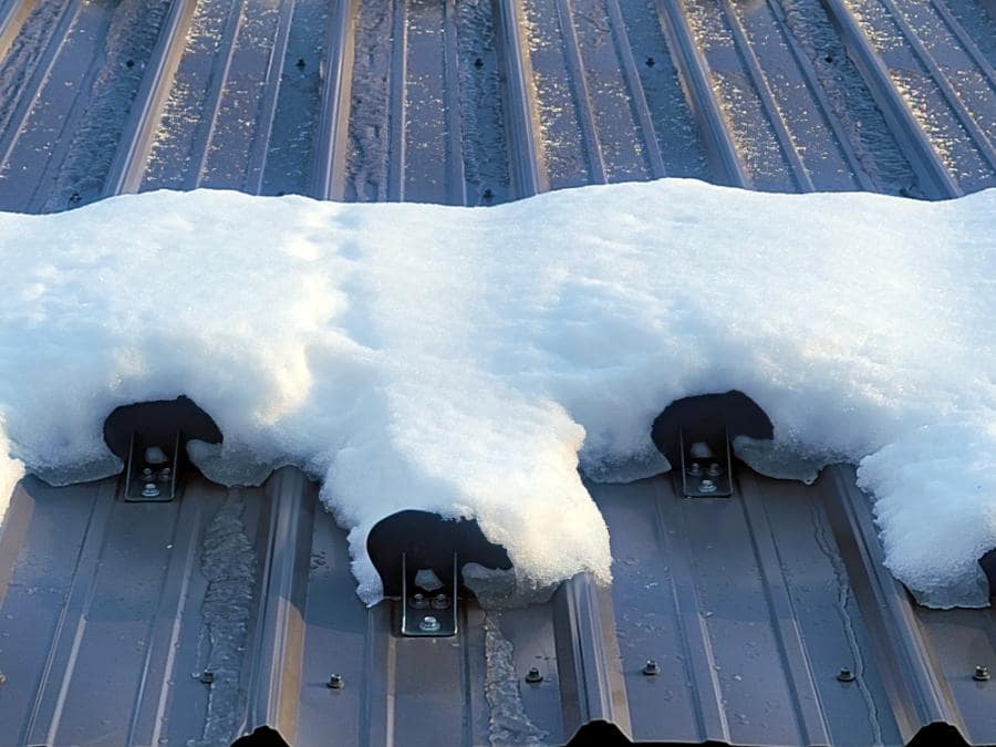Closeup view of a single staggered row of Color Matched SnowCatcher Kodiak snow guards holding snow