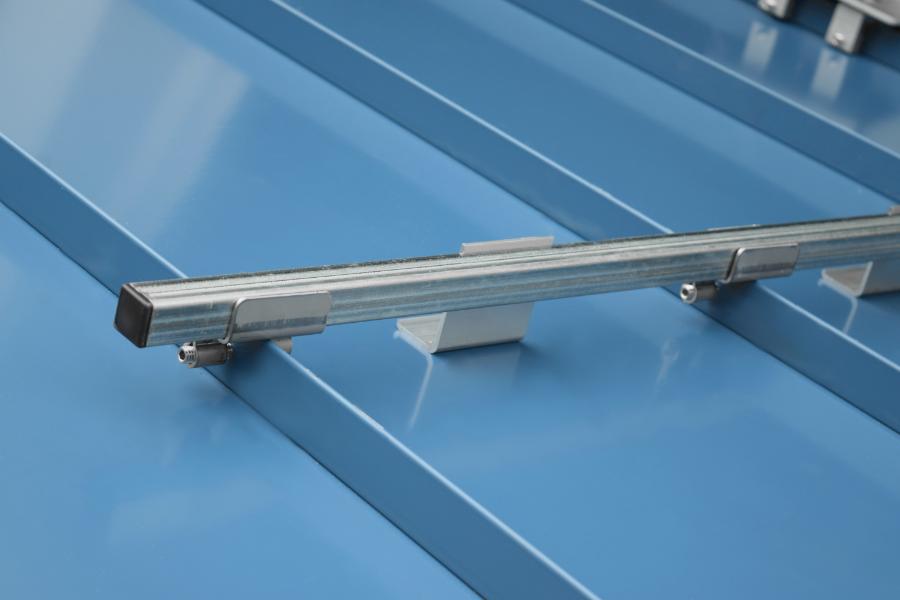 Section of mill finish galvanized SnoBar mounted on blue standing seam metal roof with IceStopper attachments installed