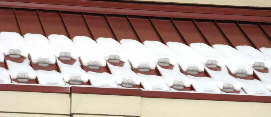 Snojax 2 Layout mounted on maroon standing seam roof panel with adhesive holding snow