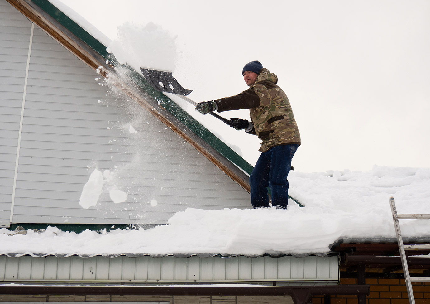 Image showing man shoveling snow off of roof. 