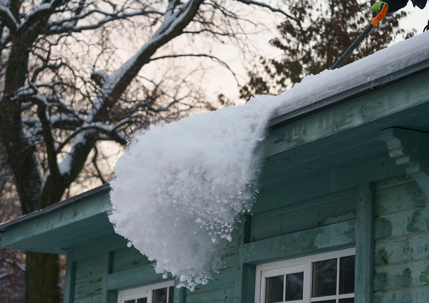 Image shows snow and ice being removed from a roof. 