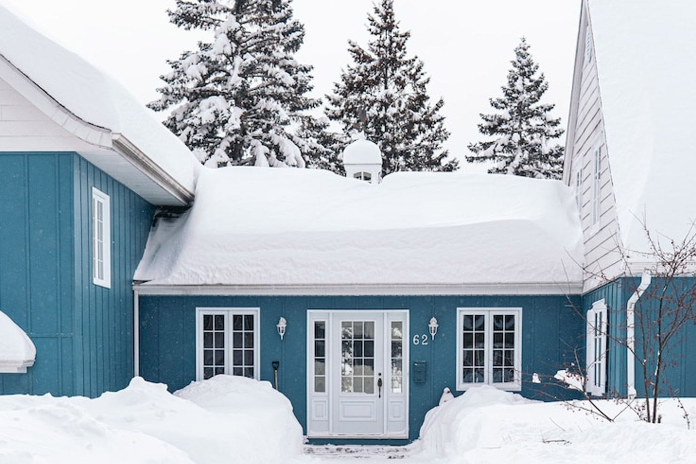 IMage showing multiple feet of snow on a teal colored home. 