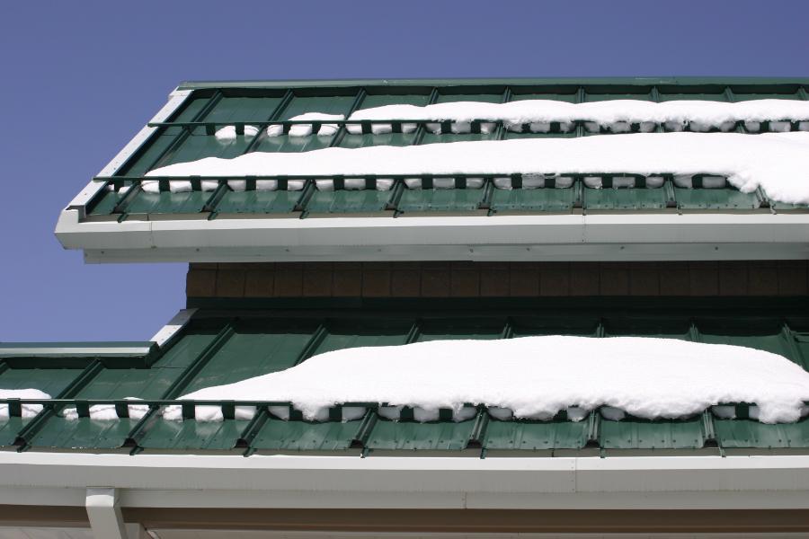Multiple Rows of SnoBar With IceStoppers Mounted on Green Standing Seam Roof Holding Snow and Ice